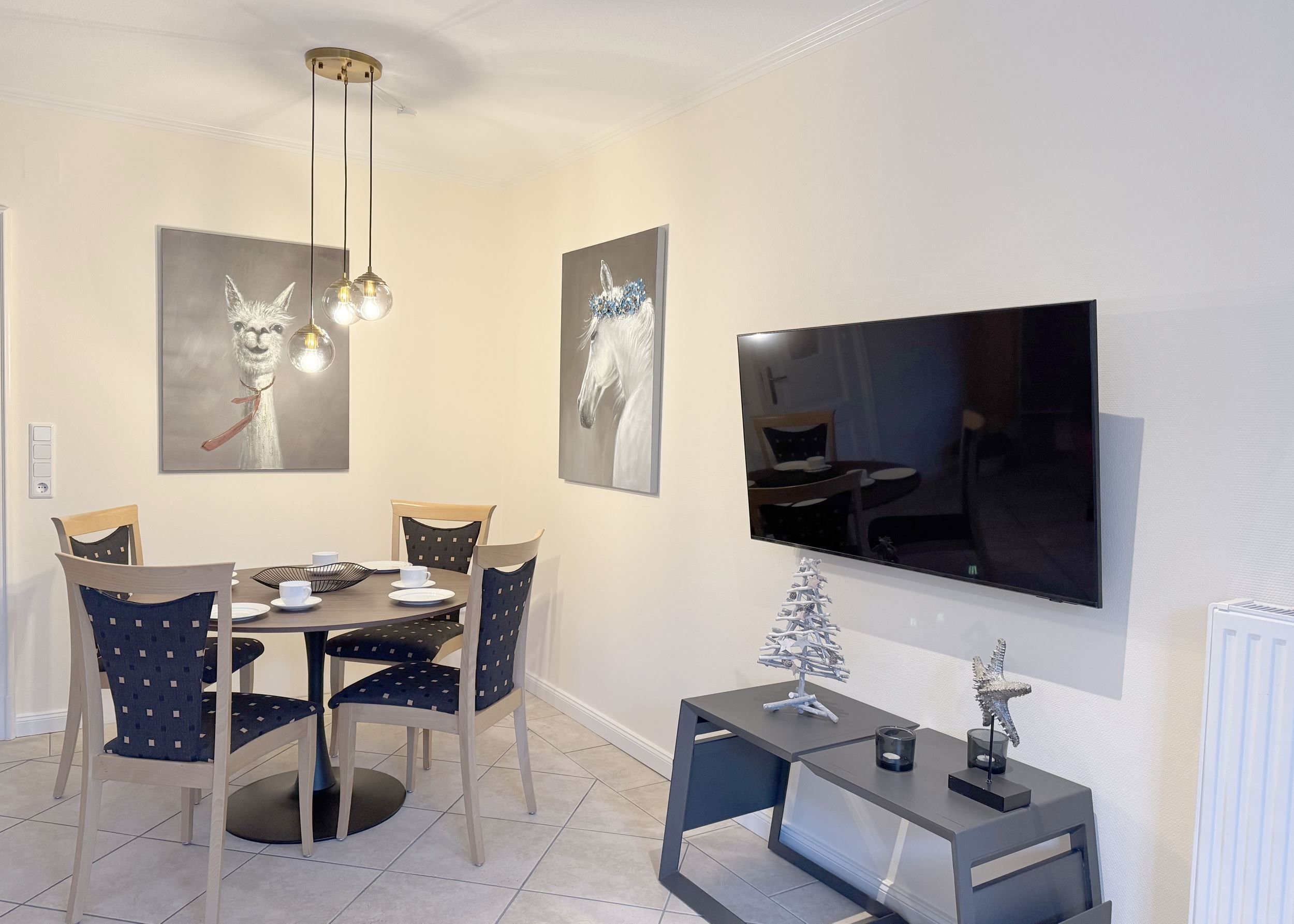 Een eetgedeelte met een ronde tafel, stoelen, een televisie en kunstwerken aan de muren.