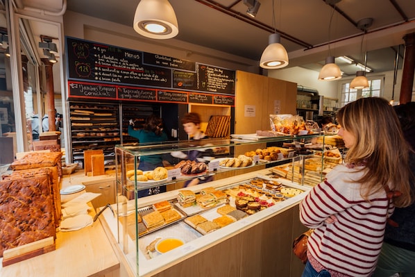 A bakery counter with various baked goods and a menu board.