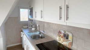 Eine moderne Küche mit weißen Schränken, Edelstahlgeräten und einem Fenster, das für natürliches Licht sorgt.