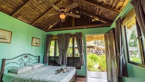 A bedroom with a bed, a ceiling fan, and a view of the outside. - 1511 Coconut Grove (Tioman Island)