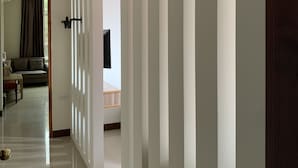 Un pasillo con diseño moderno, con una puerta de cristal que da a una sala de estar con sofá y televisor.