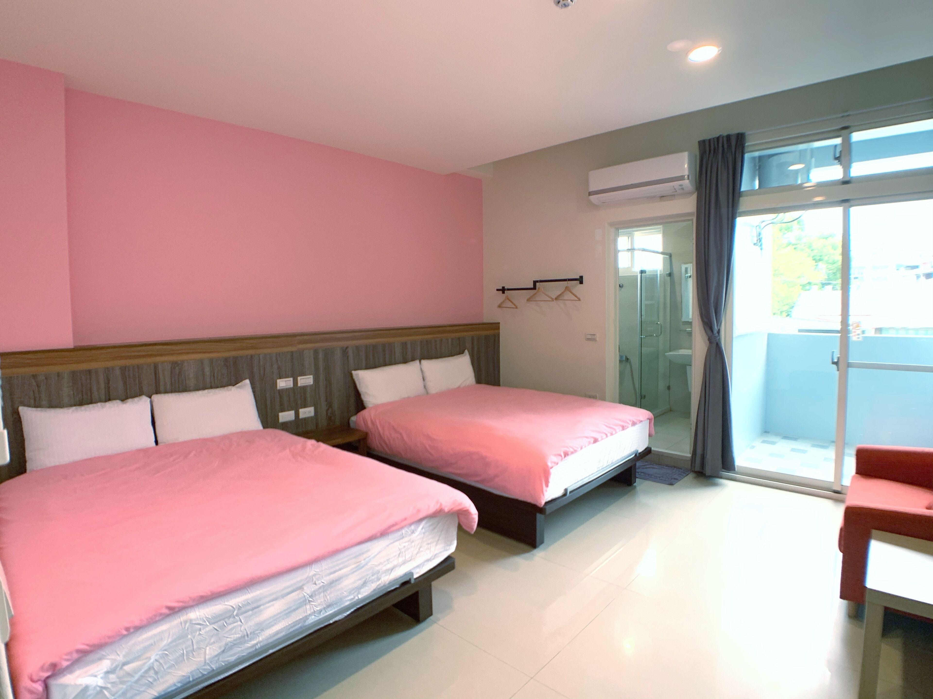 Habitación de hotel con dos camas, zona de ducha y balcón.