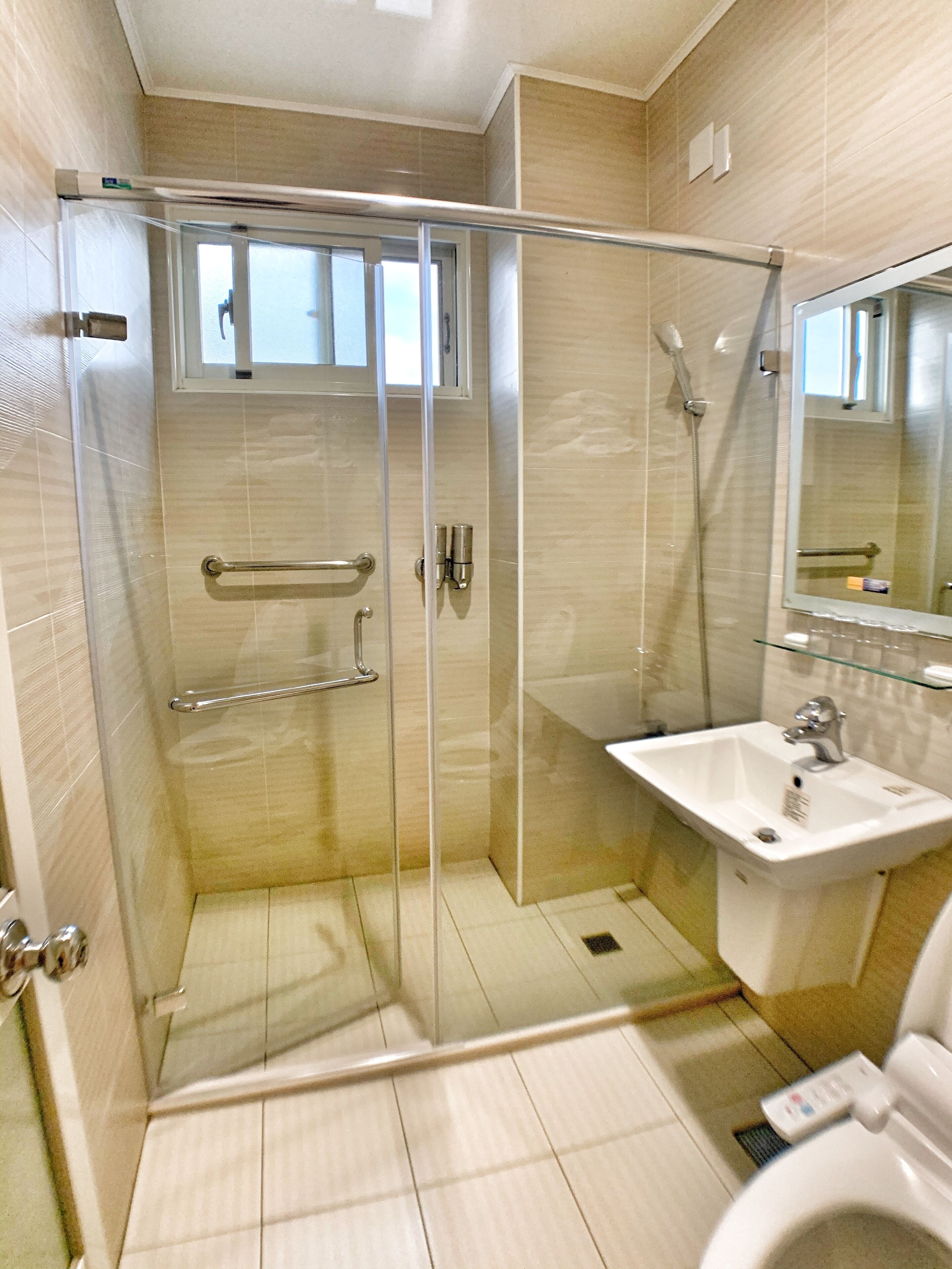 A modern bathroom with a glass-enclosed shower, a white sink, and a mirror.
