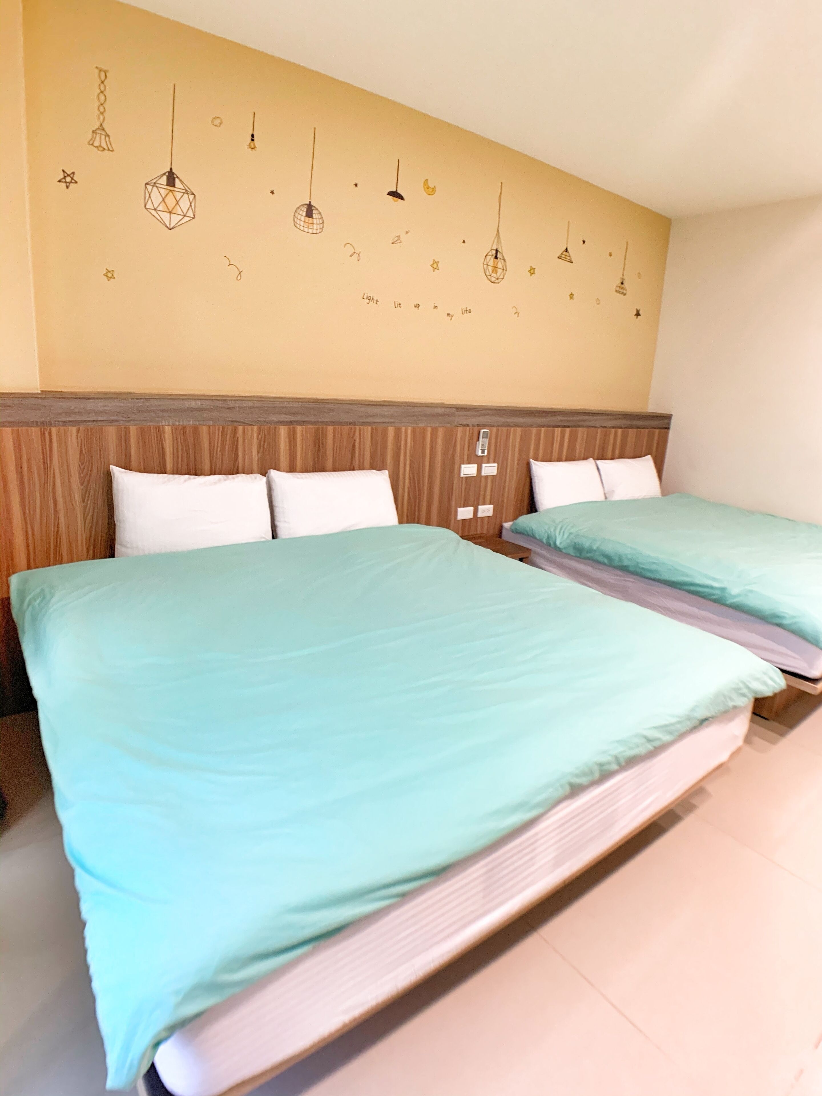 Een hotelkamer met twee bedden, een houten hoofdbord en decoraties aan de muur, waaronder hanglampen en sterren.