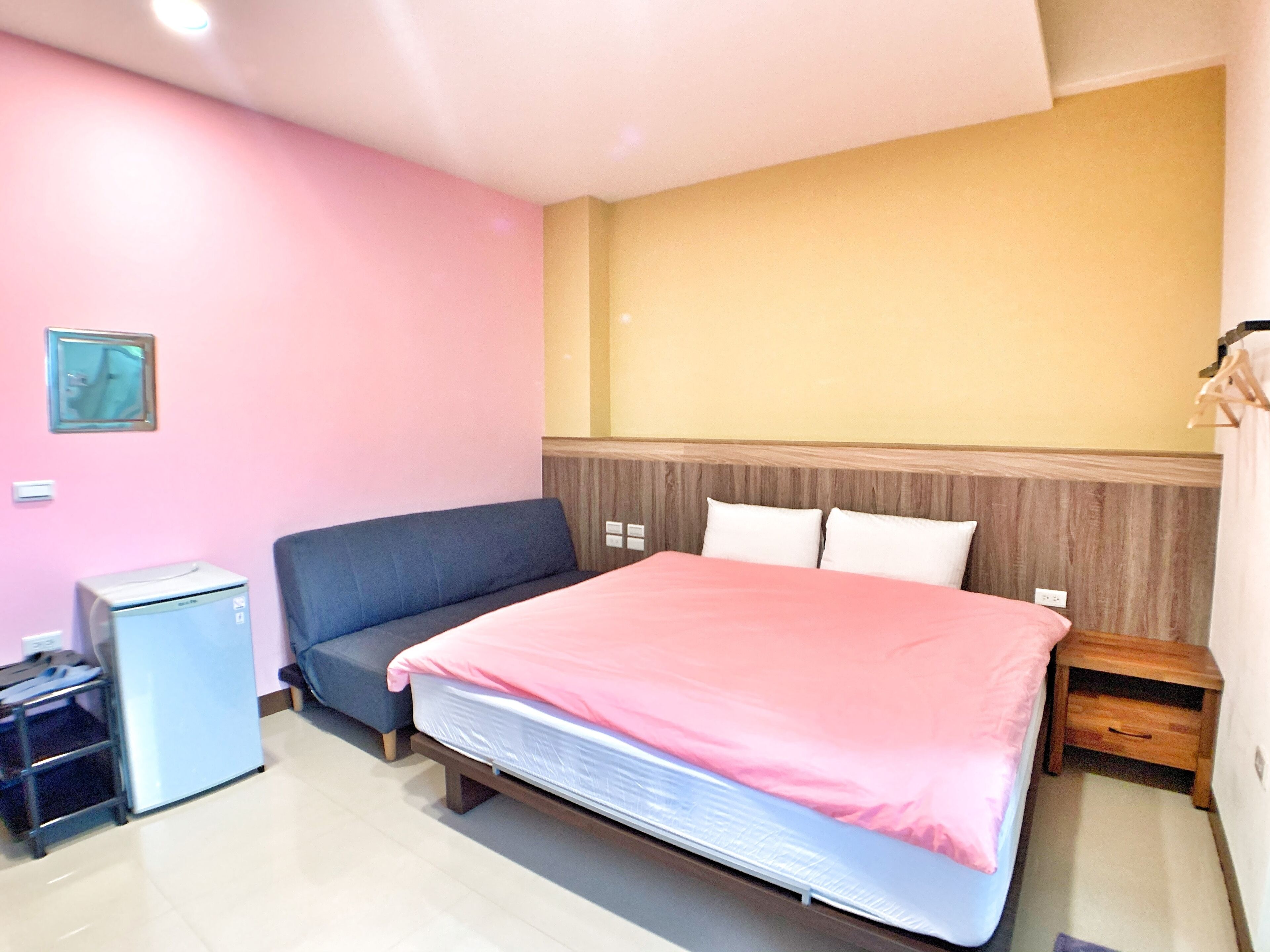 A bedroom with a bed, a small desk, a chair, and a heater.