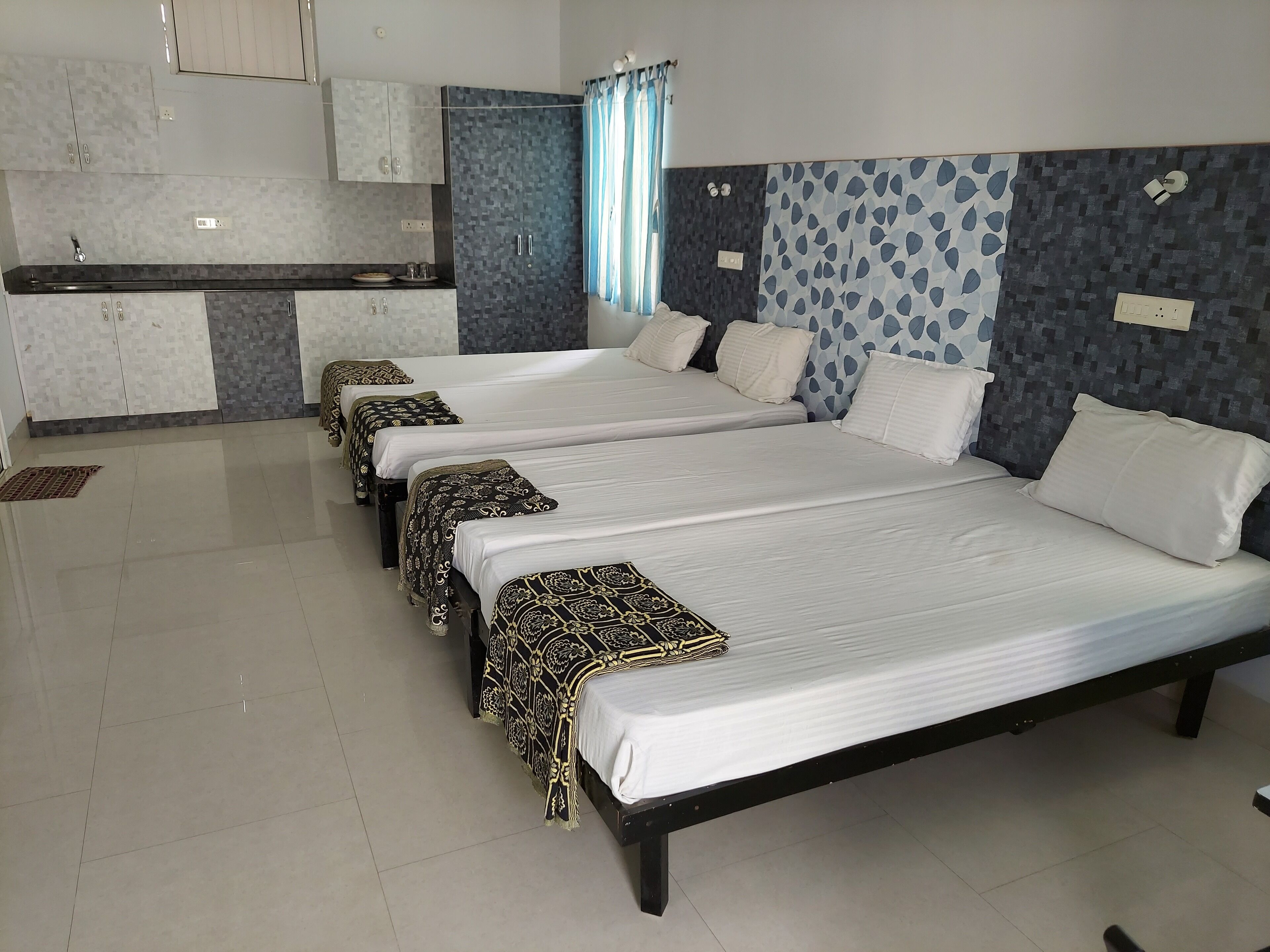 Una habitación de hotel con tres camas, kitchenette y baño.