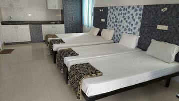 Una habitación de hotel con tres camas, kitchenette y baño.