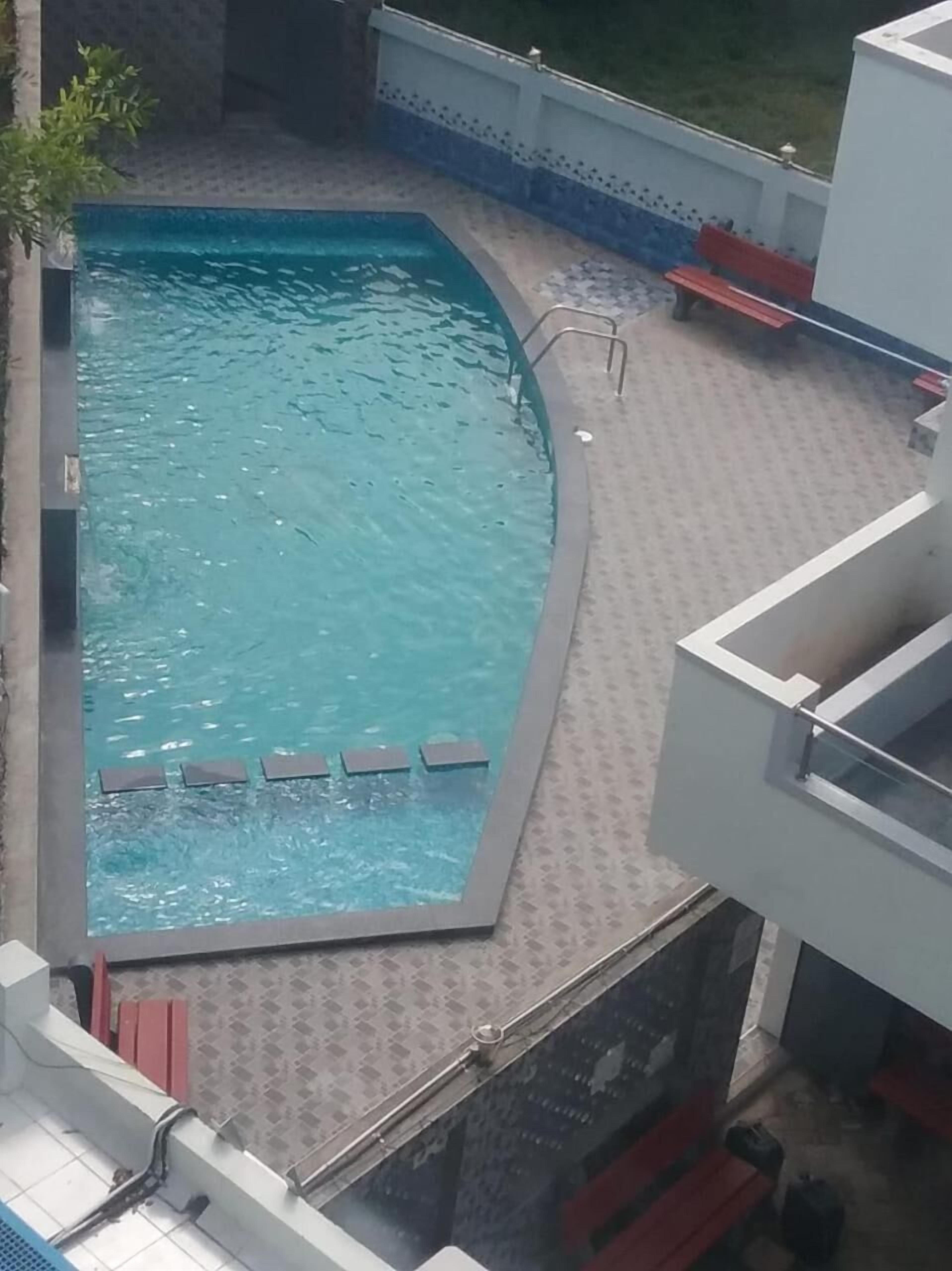 A swimming pool with a tiled deck and a few lounge chairs.