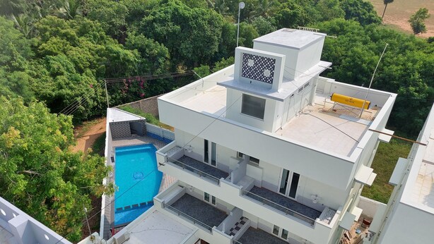 A multi-story building with a rooftop pool, balconies, and a satellite dish. - Quiet Home Pondy (Vanur)