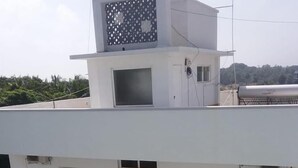 A multi-story building with balconies, windows, and a rooftop water tank. - Quiet Home Pondy (Vanur)
