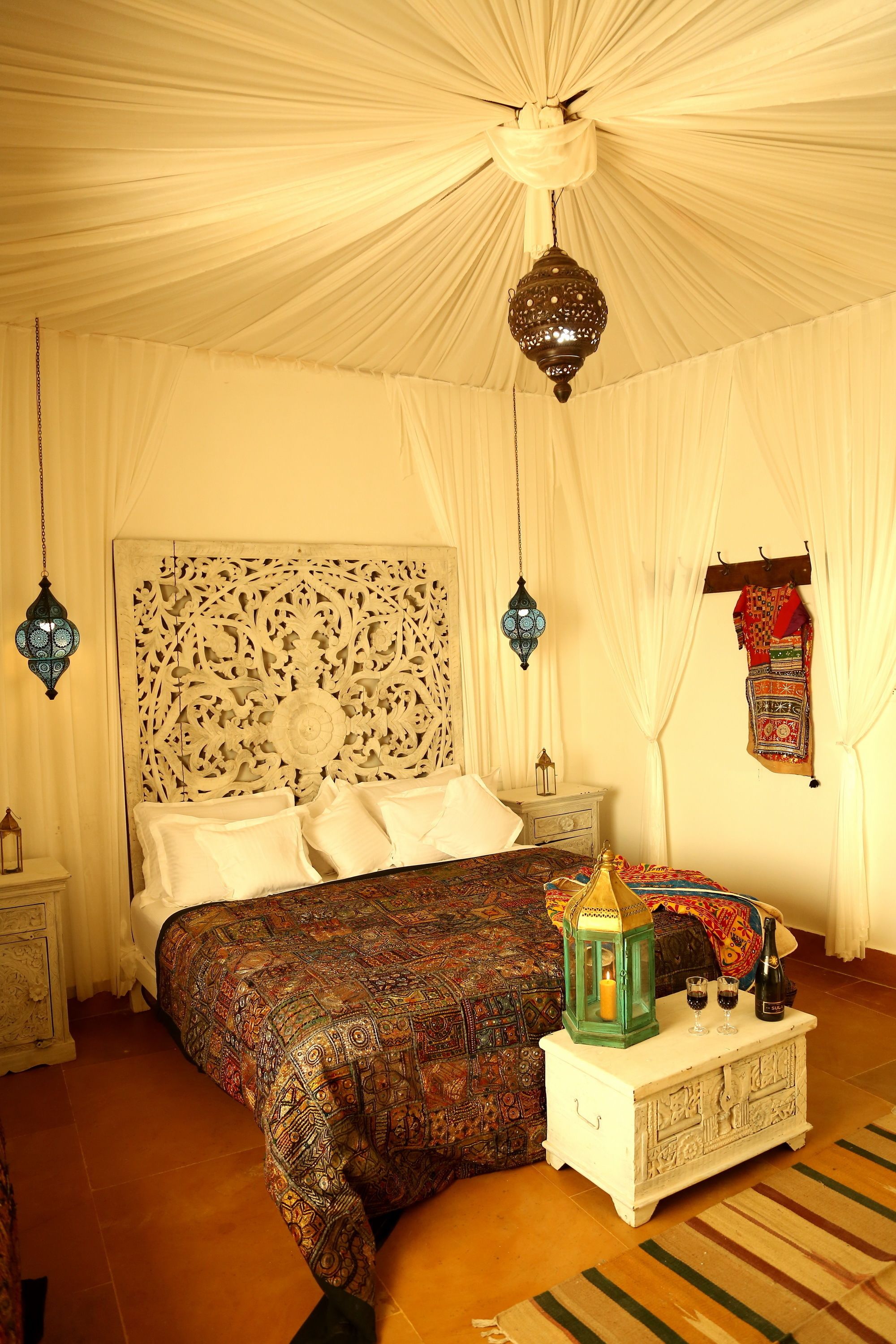 A bedroom with a bed, a nightstand, a decorative lantern, and a hanging garment.