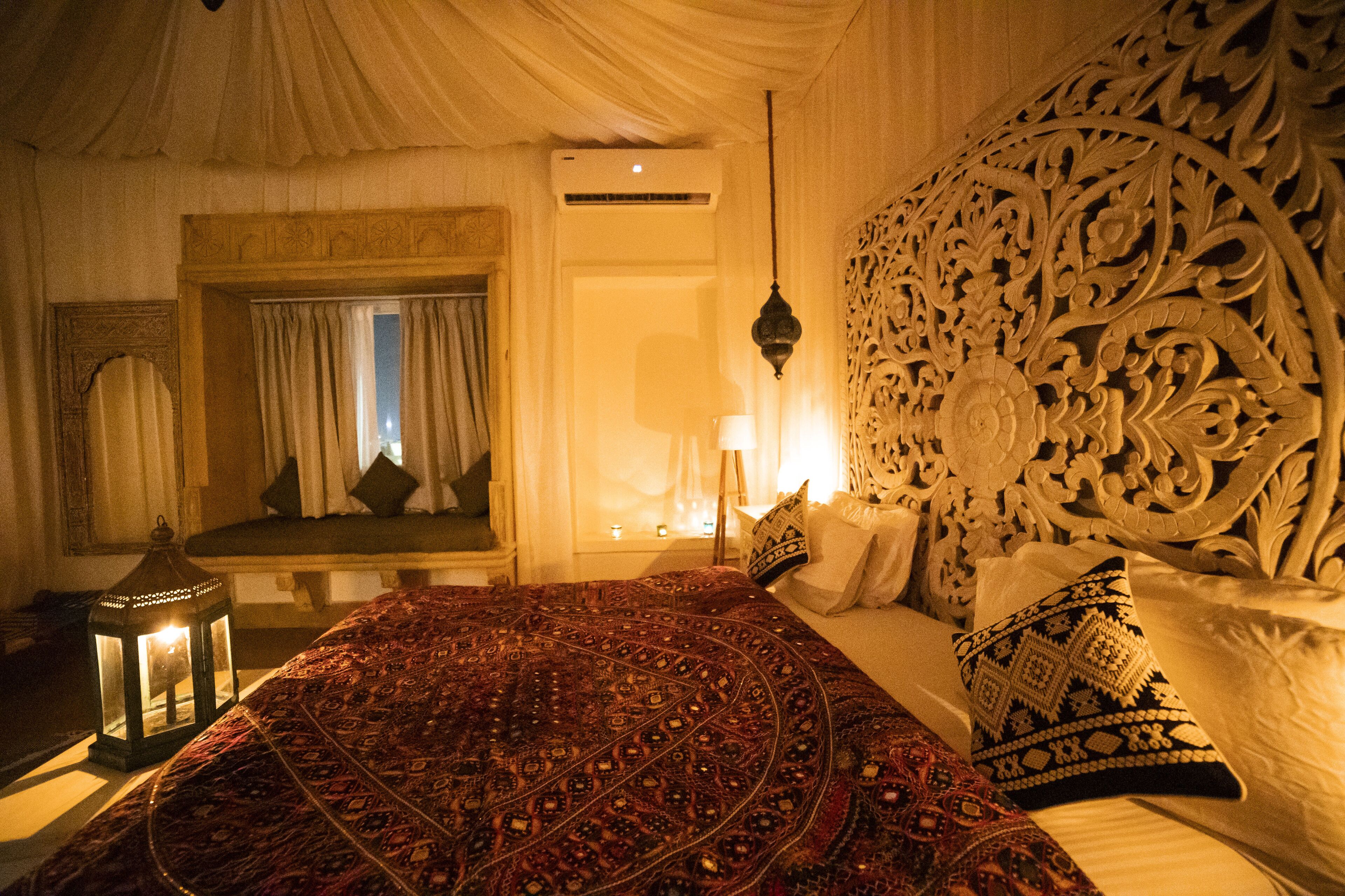 A room with a large bed, ornate headboard, and a decorative lantern.
