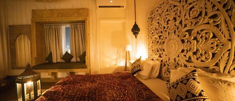 A room with a large bed, ornate headboard, and a decorative lantern.