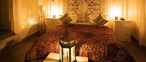 A room with a bed, a nightstand, a lamp, and a hanging lantern.
