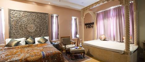 A bedroom with a large bed, a smaller bed, a chair, and a ceiling fan.
