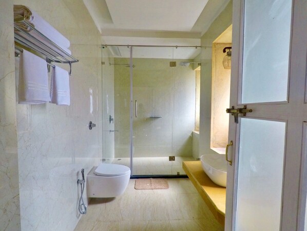 Un baño moderno con ducha envuelta en vidrio, inodoro y una bañera grande.