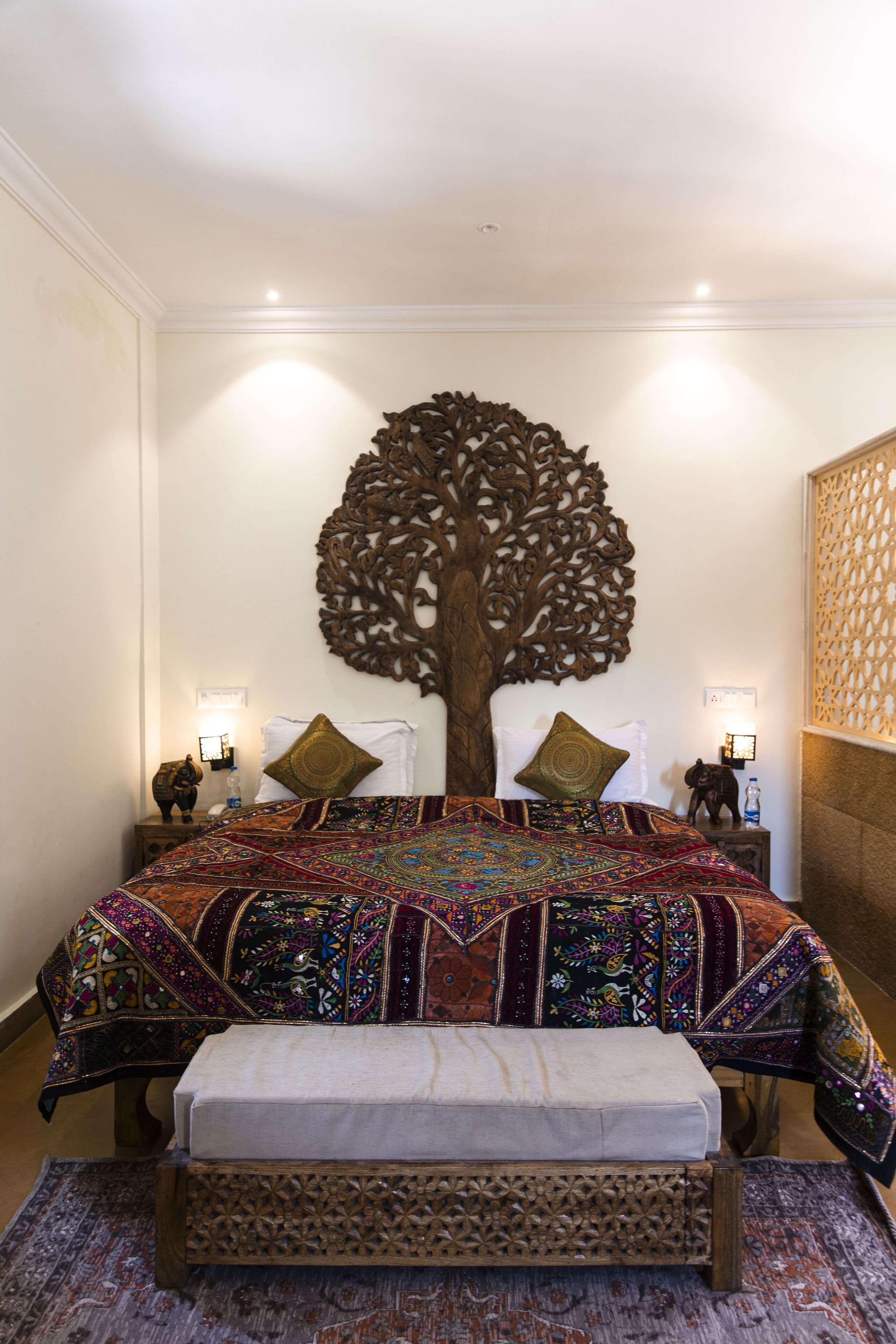A bedroom with a large bed, ornate headboard, and a bench.
