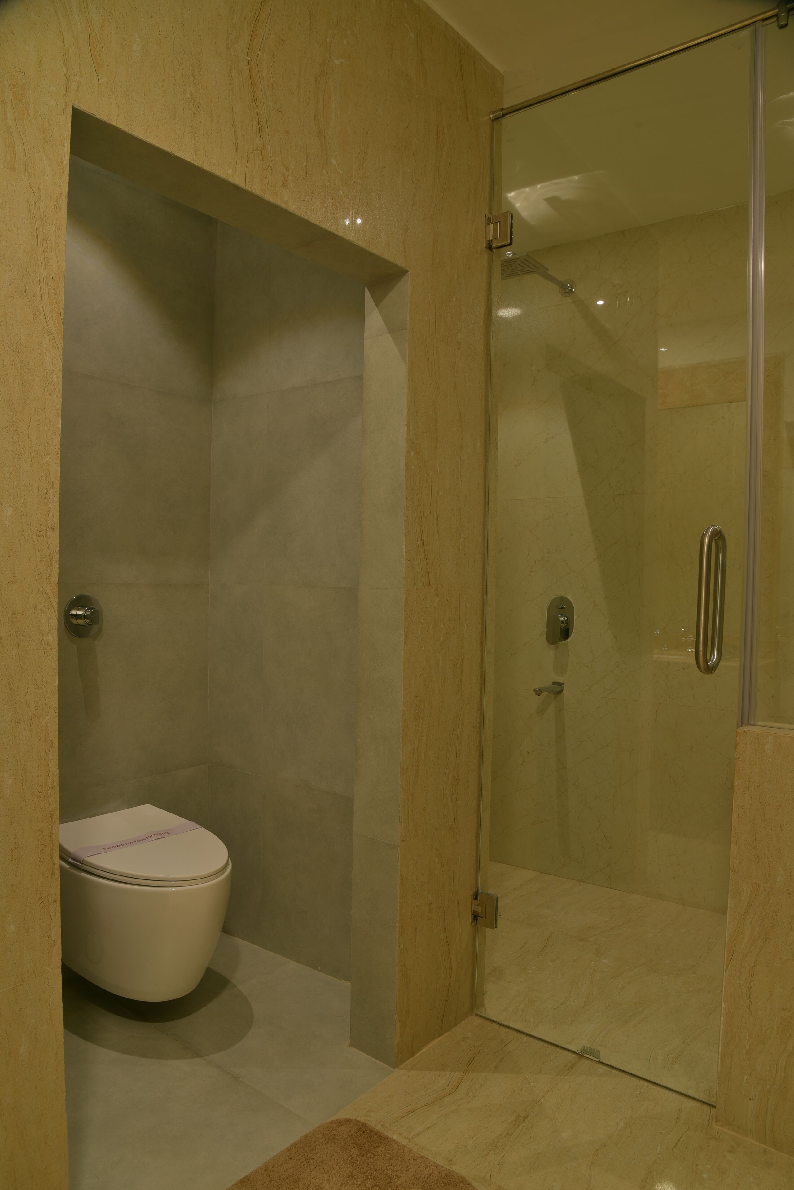 A modern bathroom with a glass-enclosed shower, a toilet, and a marble floor.