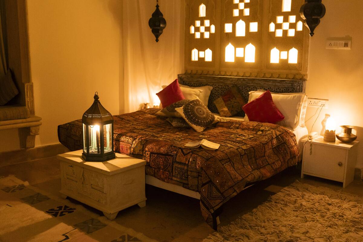 Een gezellig slaapkamer met een bedovertrek met een patroon, een nachtkastje met een lamp en een decoratieve muur met geometrische patronen.