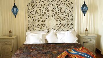 Un lit avec une couvre-lit à motifs, une tête de lit décorative et deux lanternes suspendues.