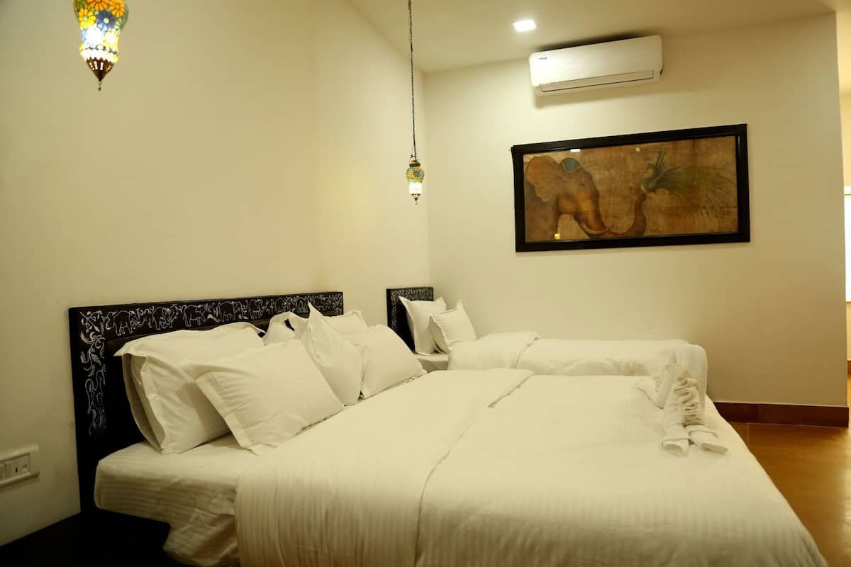 Een hotelkamer met een groot bed, een hoofdeinde met een decoratief patroon, een wandairconditioner en een kunstwerk in een lijst boven het bed.