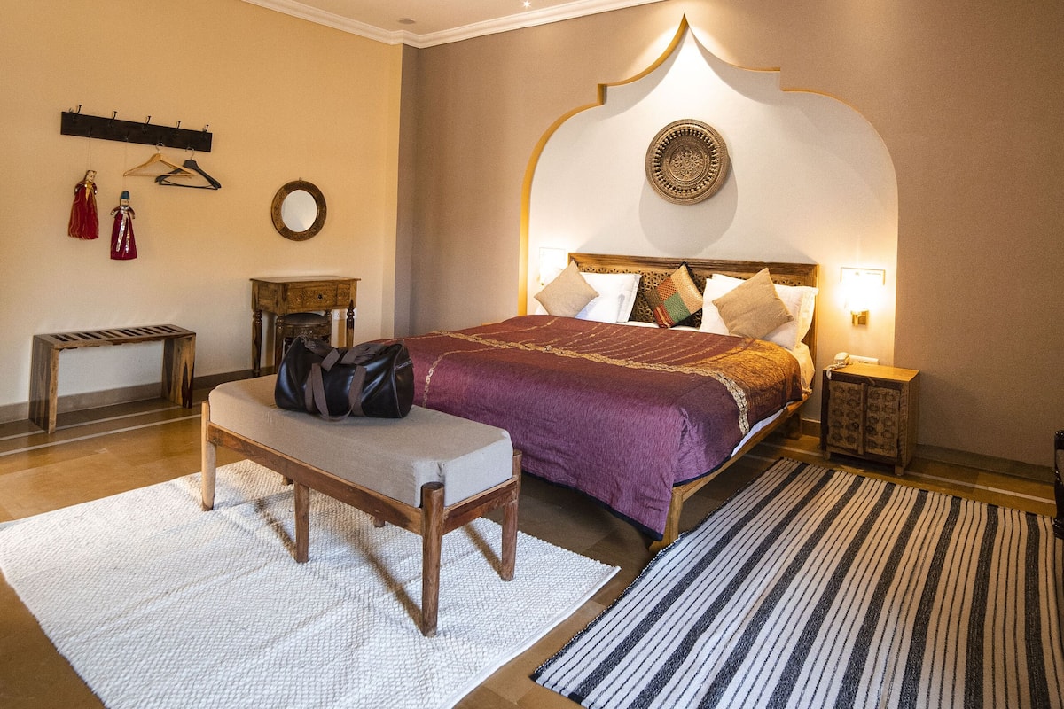 Een slaapkamer met een bed, nachtkastjes, een kapstok, een spiegel en een plafondventilator.