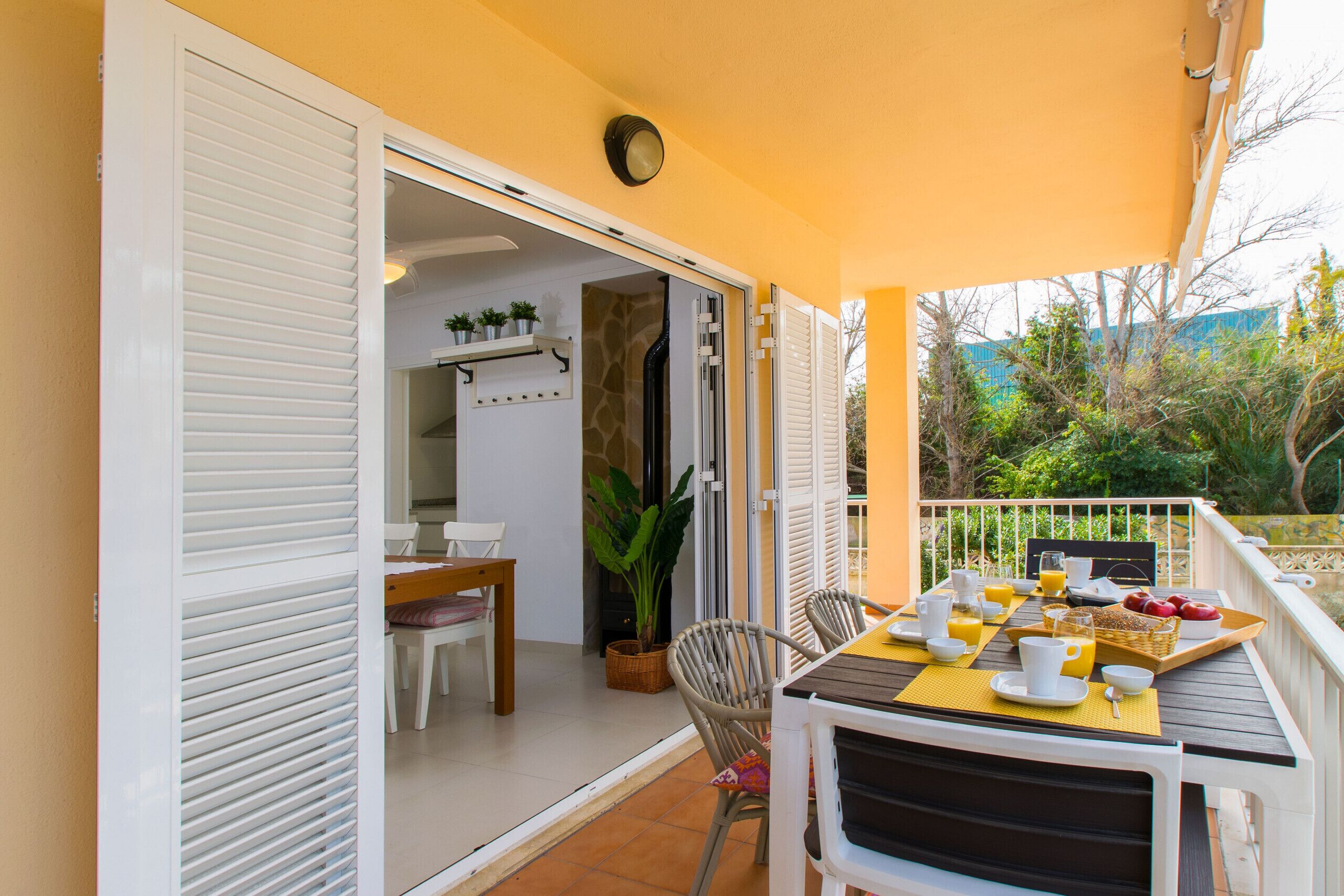 Un espace de restauration en plein air avec une table dressée pour le petit-déjeuner, une plante en pot et une vue sur le jardin.