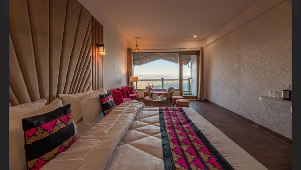 A hotel room with a large bed, a sofa, a balcony with a view, and a dining area. - Hotel Robinsson Palace (Kosiyakutoli)