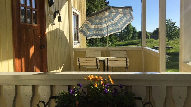 En veranda med en trædør, en bænk og et bord.