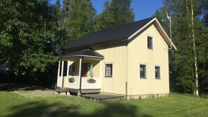 Et toetagers hus med en veranda, omgivet af træer.