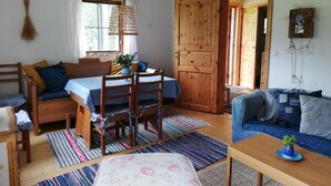 Et hyggeligt værelse med seng, spisebord med stole, sofa og en trædør.