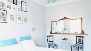A bedroom with a bed, two chairs, a round table, a mirror, and wall art. - Colosseum Acquaforte's Room (Rome)