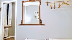 A room with a large ornate mirror, a radiator, a white door, and a wooden coat rack. - Colosseum Acquaforte's Room (Rome)