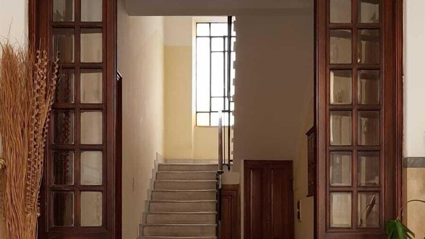 A staircase leading to a room with a patterned floor and a window with bars. - Colosseum Acquaforte's Room (Rome)