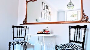 A room with two zebra-patterned chairs, a white table with a tray of items, and a large mirror with an ornate frame. - Colosseum Acquaforte's Room (Rome)