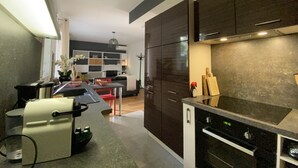 A modern kitchen with dark cabinets, a black countertop, and a built-in oven.