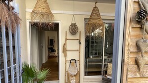 A cozy entrance with a wooden door, a potted plant, and a wicker chair.