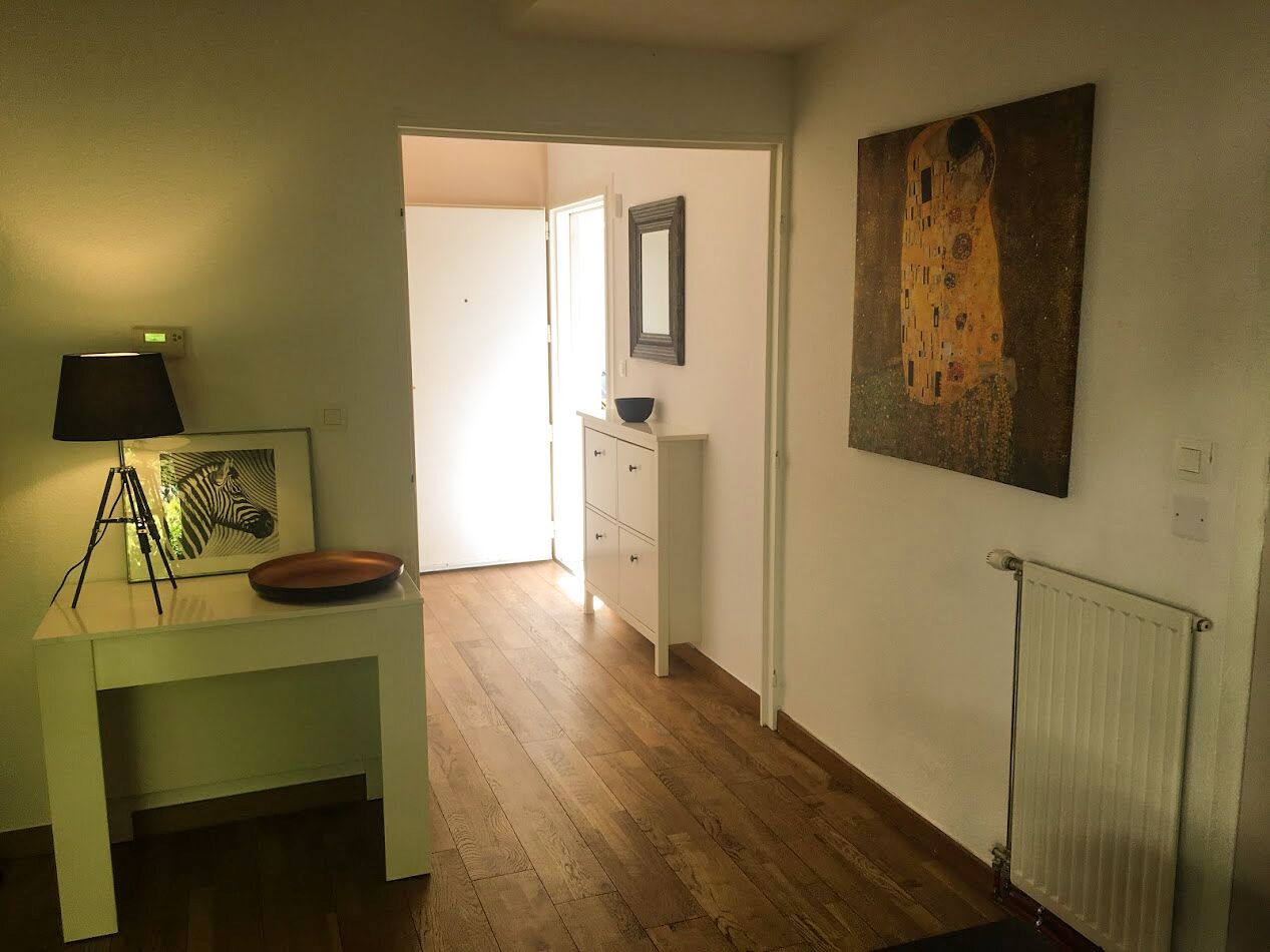 A hallway with a desk, lamp, and framed artwork.