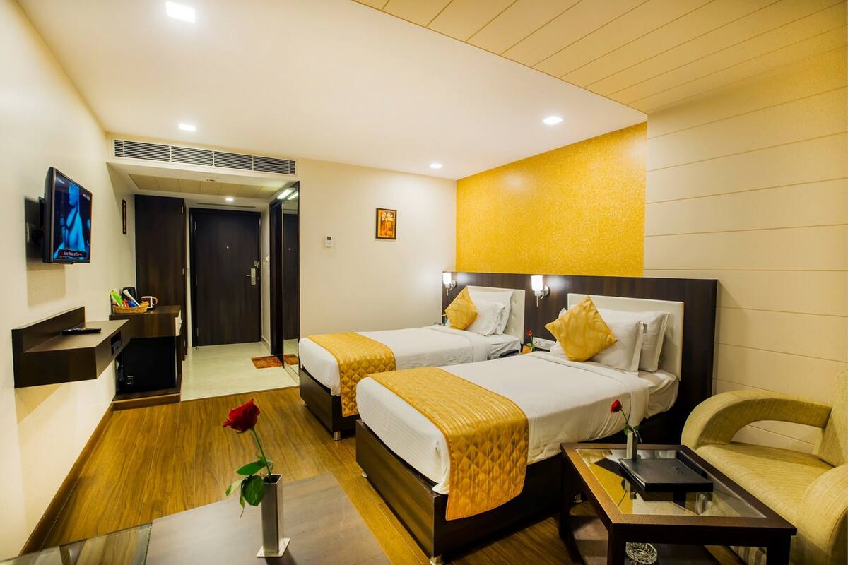 A hotel room with two beds, a sofa, a TV, and a desk.