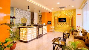 A hotel lobby with a reception desk, seating area, and a TV screen. - Hotel Kapish Smart (Jaipur)