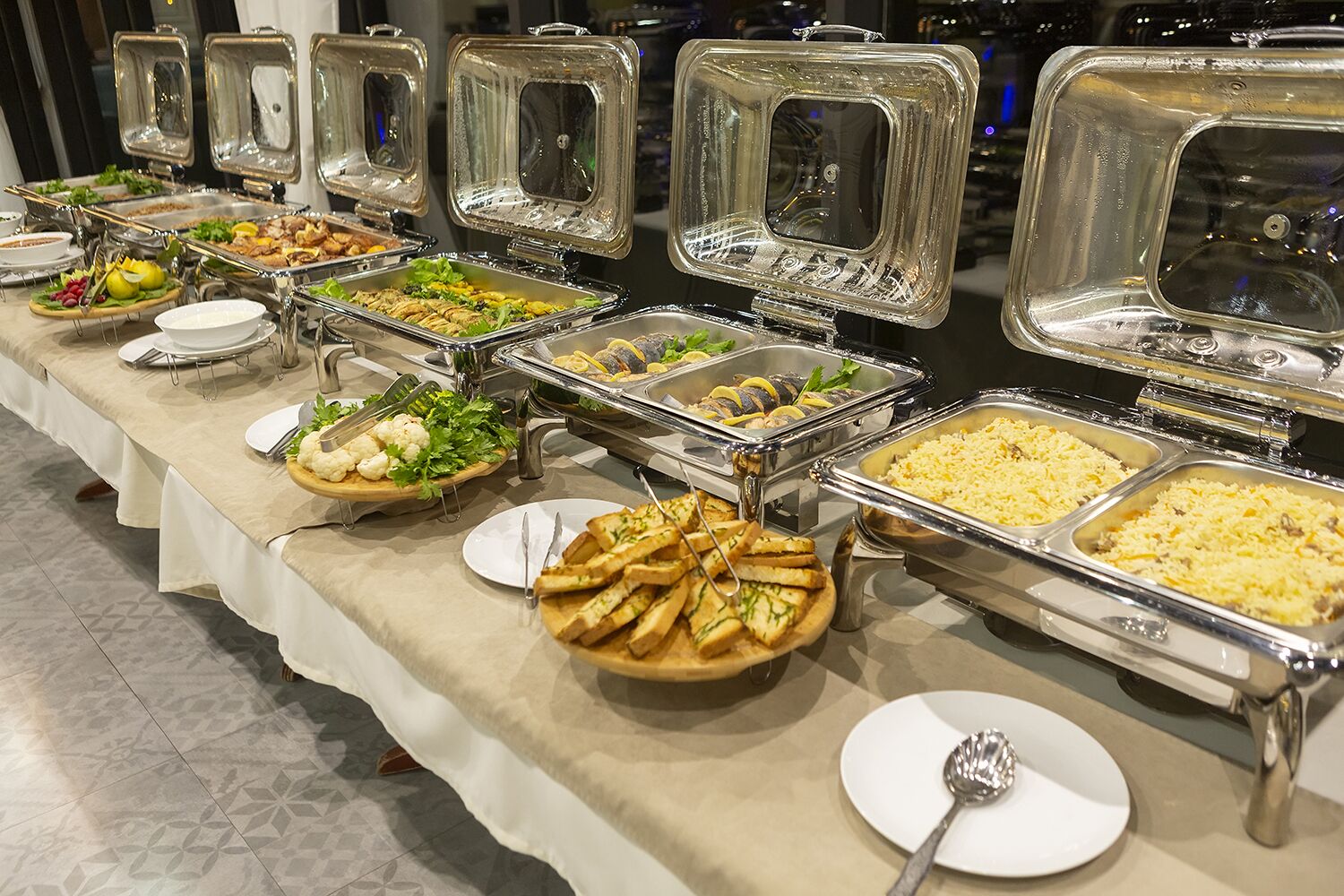 A buffet with various food items and utensils.