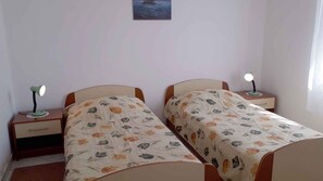 A bedroom with two single beds, each with a nightstand and a lamp. - Holiday apartment with use of pool (Novi Vinodolski)