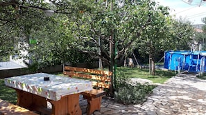 A wooden bench and picnic table in a garden with a stone pathway. - Holiday apartment with use of pool (Novi Vinodolski)