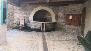 A stone-walled room with a stone fireplace, a bench, and a wooden door.