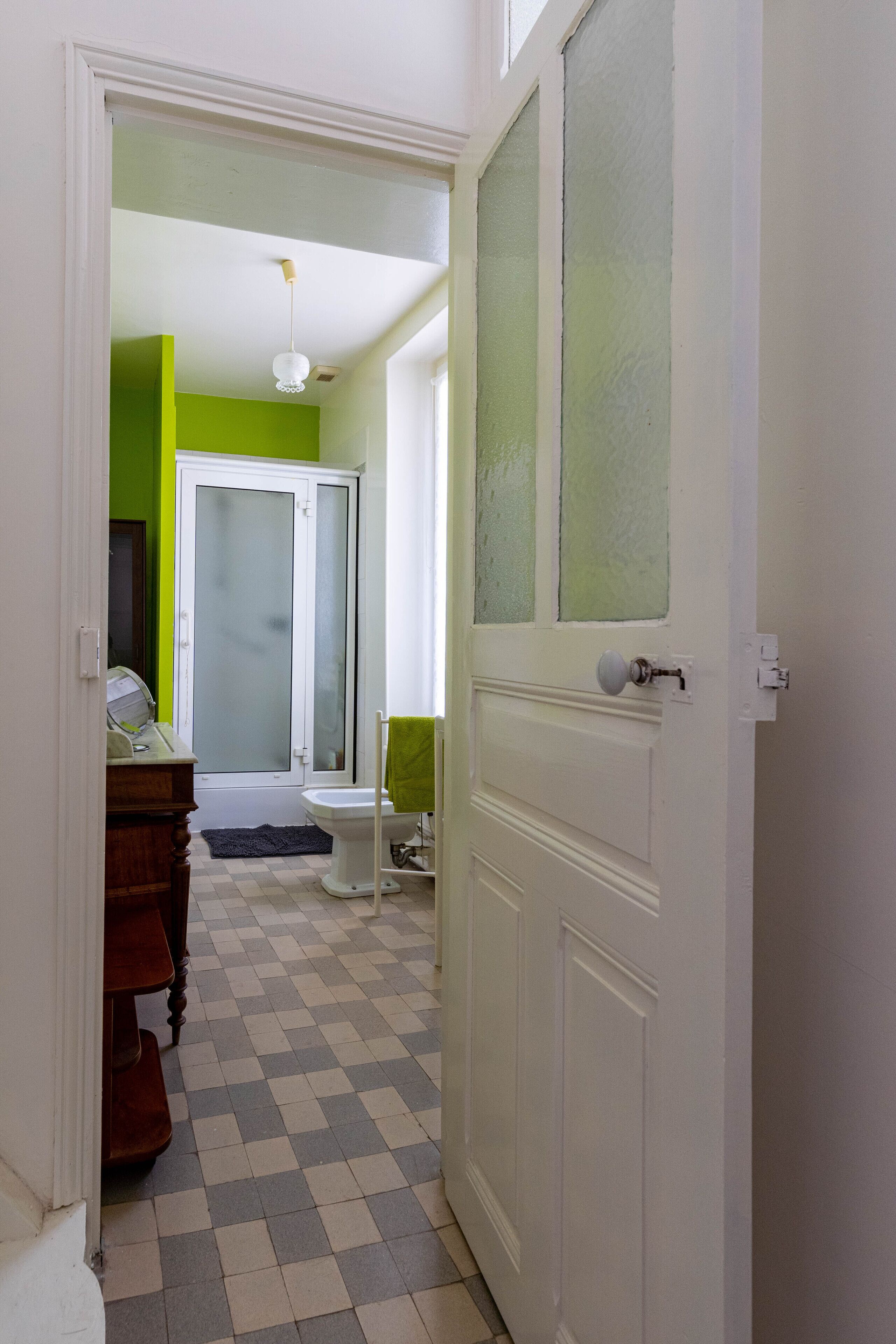 A hallway with a checkered floor, a white door, and a green wall.