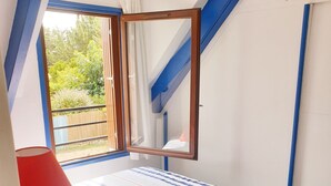Ein Schlafzimmer mit Bett, Fenster und Blick auf Grün.