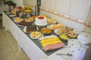 A buffet table with various food items including cakes, pastries, and cheeses.