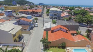 A coastal town with a mix of residential and commercial buildings, a clear road, and a visible swimming pool.