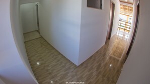 A hallway with a tiled floor and white walls, leading to a door at the end. - Pousada Sol de Maria (Penha)