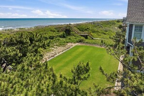 Un parcours de golf offrant une vue dégagée sur l’océan, entouré d’une forêt dense de pins et traversé par un pont en bois.